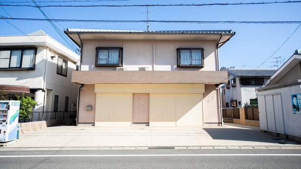 A two-story building with a garage door, a small entrance, and a visible satellite dish. - Awaji Seaside Resort in Shiduki (Awaji)