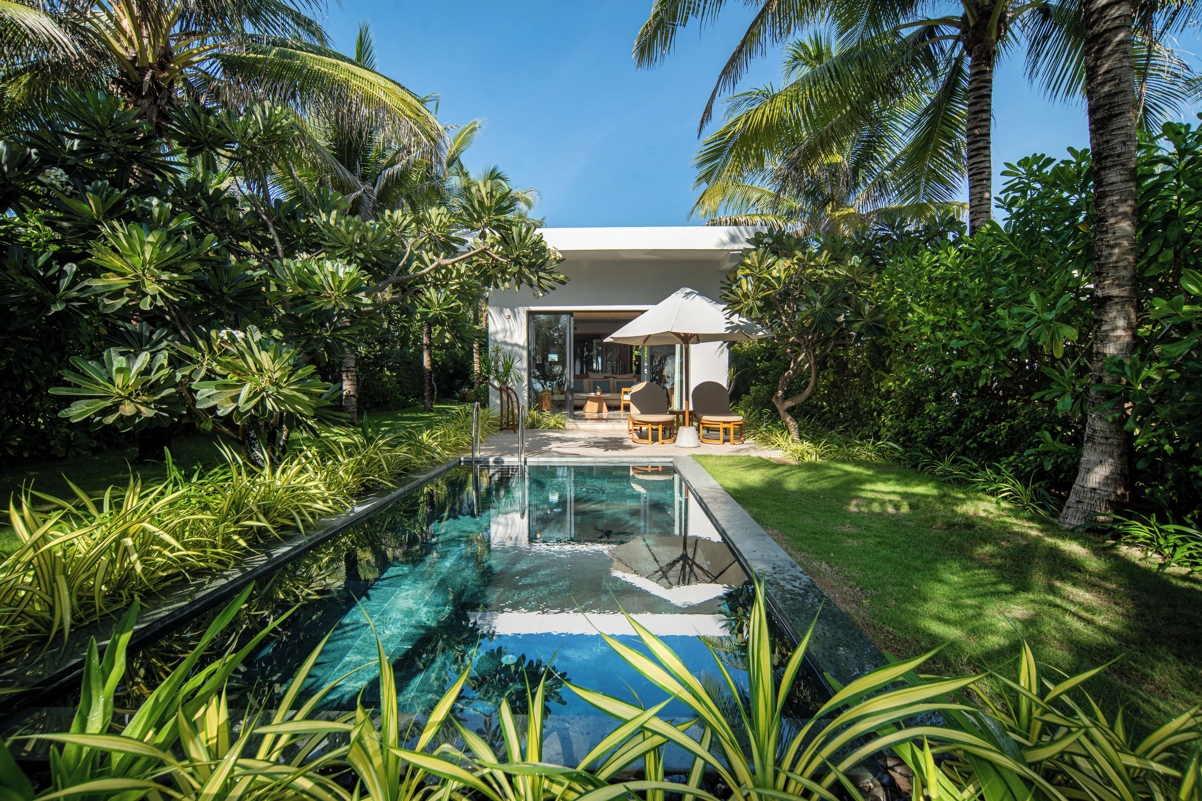 A pool surrounded by lush greenery and a modern outdoor seating area.