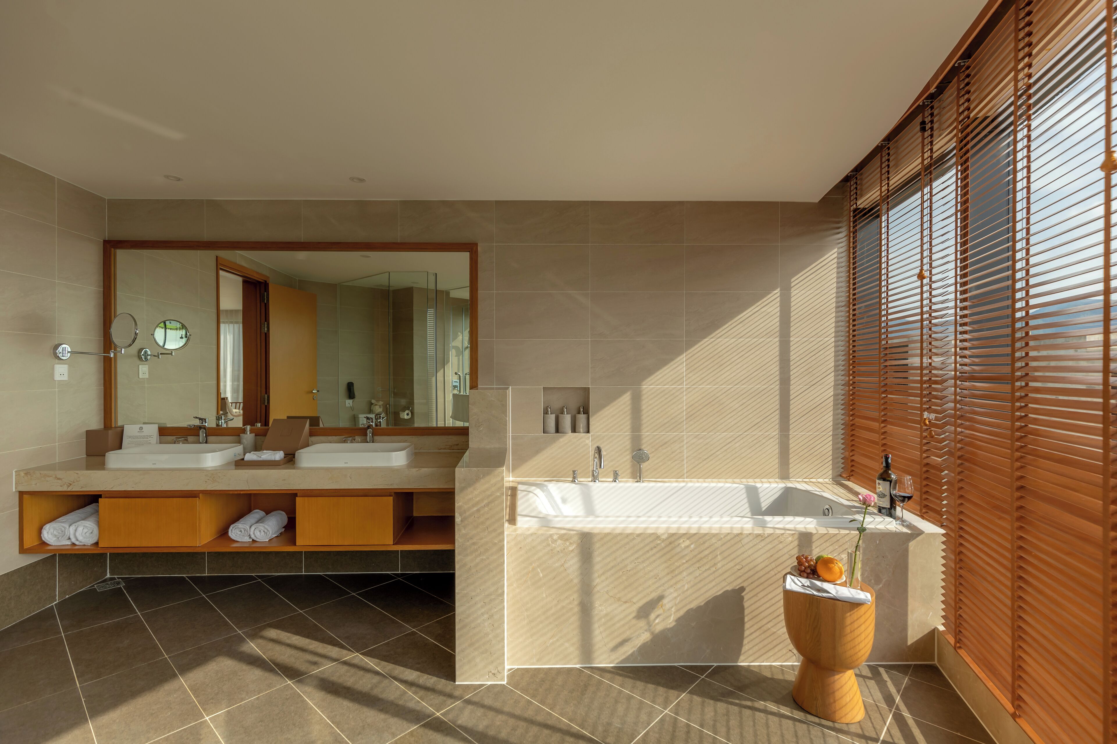 A modern bathroom with two sinks, a large bathtub, and a wooden toilet.