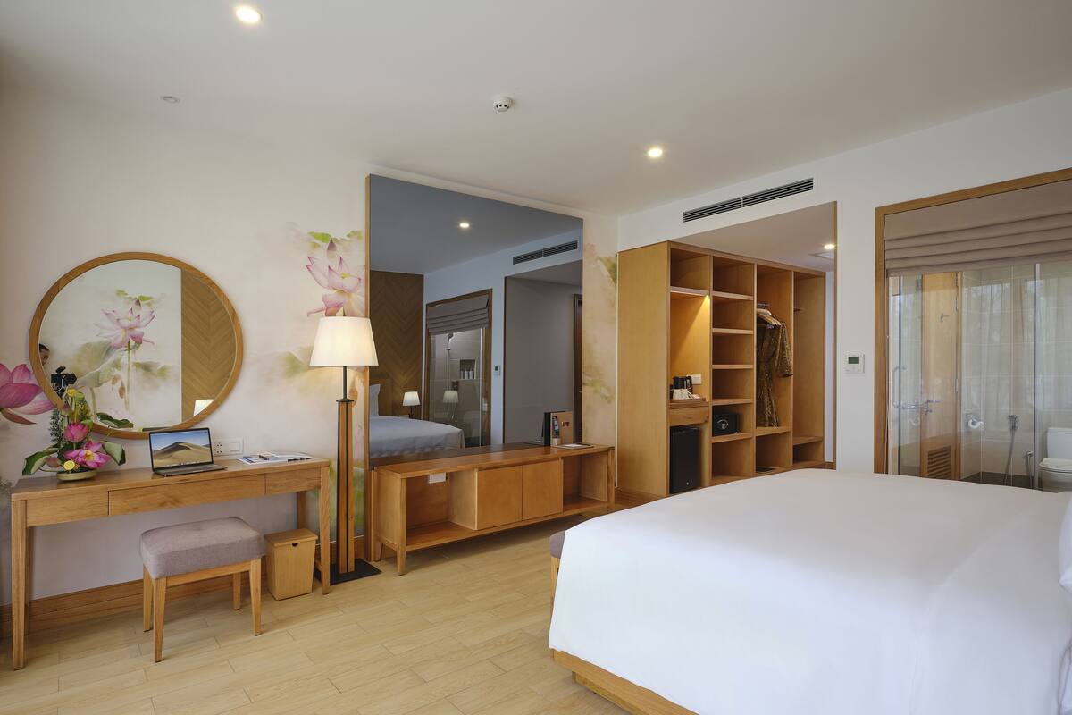 Une chambre d’hôtel équipée d’un lit, d’un bureau, d’une chaise et d’un grand miroir.