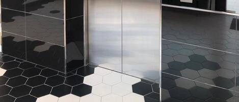 Un ascensor moderno con puertas metálicas y un panel de control digital.