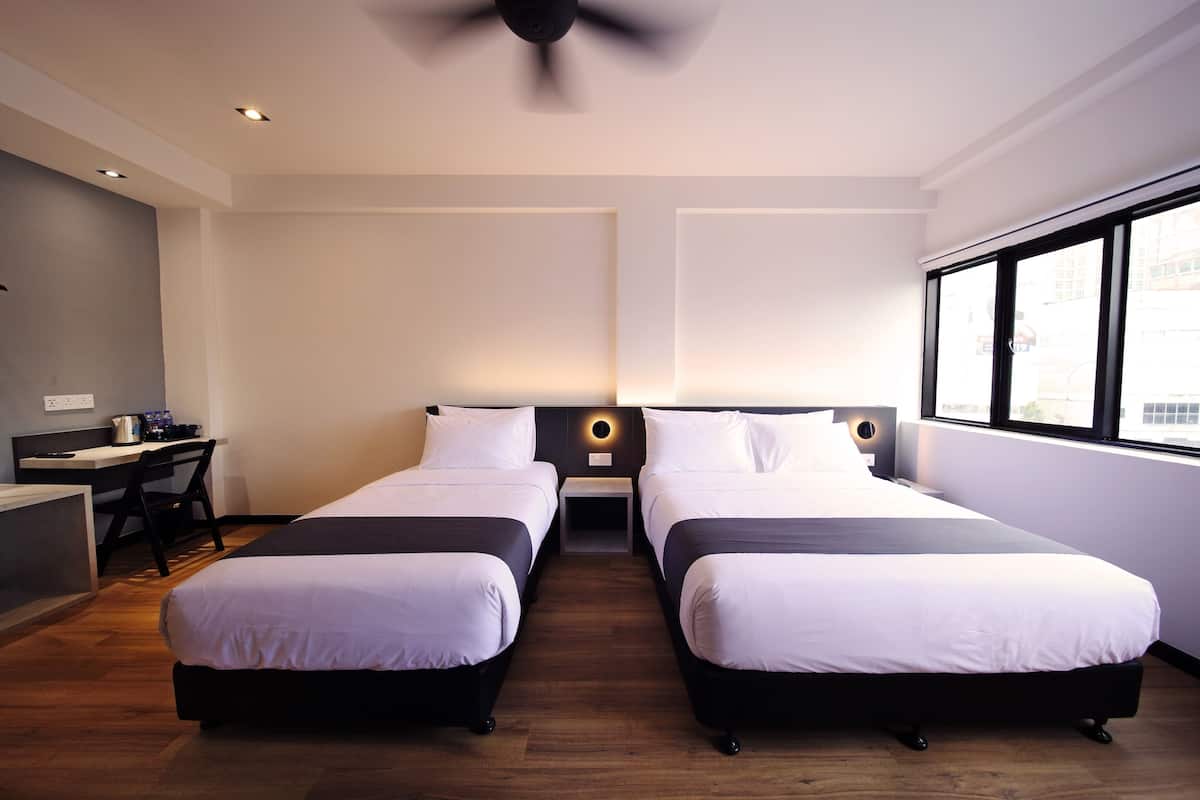Une chambre d’hôtel avec deux lits simples, un bureau et une chaise.