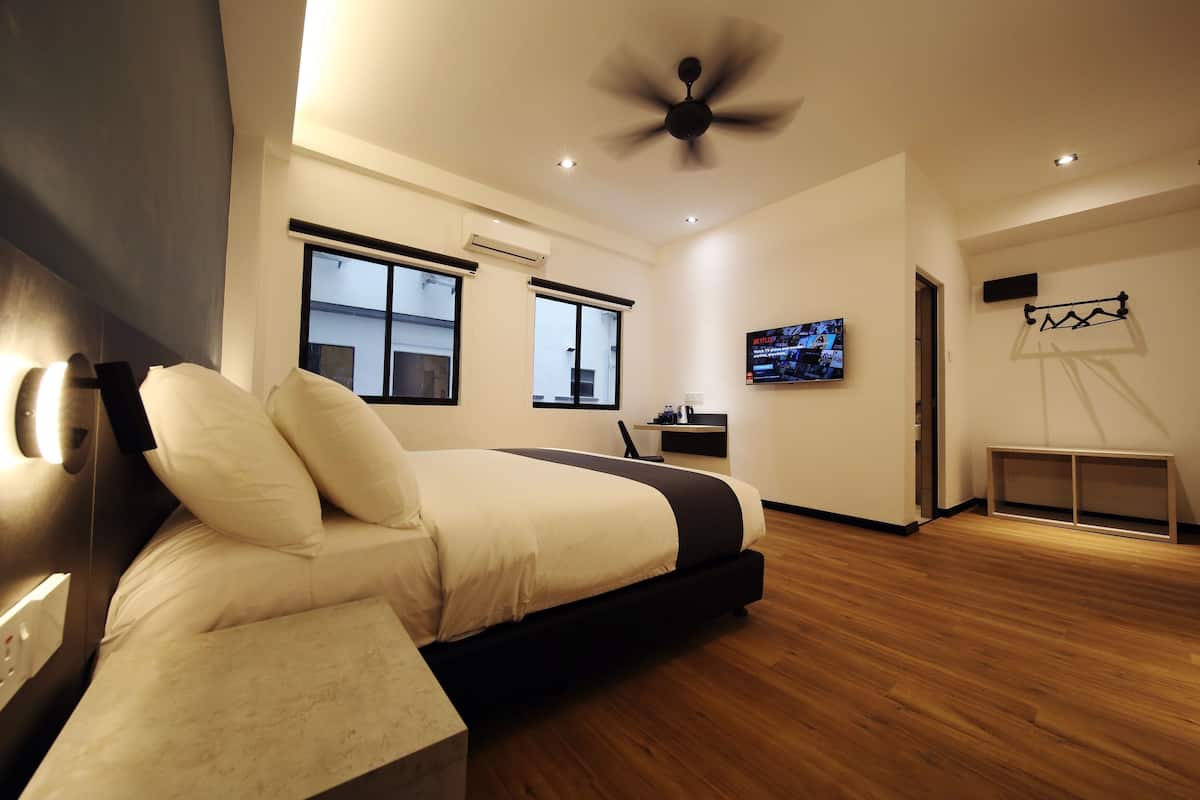 Une chambre moderne équipée d’un lit, d’un ventilateur de plafond, d’une télévision et d’un bureau.