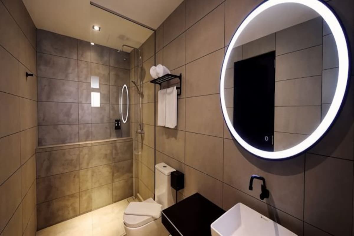 A modern bathroom with a shower, toilet, sink, and a large mirror.