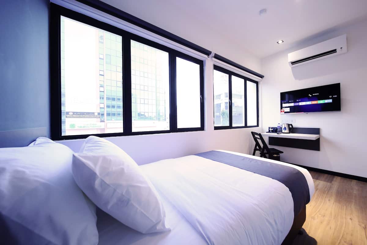 Une chambre d’hôtel moderne, dotée d’un grand lit, d’un bureau et d’un téléviseur fixé au mur.