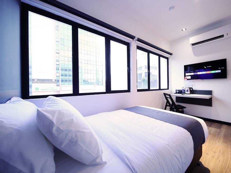 A modern hotel room with a large bed, a desk, and a TV mounted on the wall.