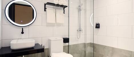 A modern bathroom with a glass-enclosed shower, a white sink, and a toilet.