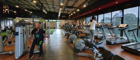 A gym with treadmills, weight machines, and a person exercising.