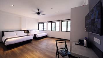 Una habitación de hotel moderna con una cama grande, una cama más pequeña, un escritorio con una silla y un televisor montado en la pared.
