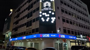 Hotellissa on selkeästi näkyvä kyltti, jossa lukee »Arena Boutique Hotel» ja jossa mainitaan myös »UOB»-pankki.