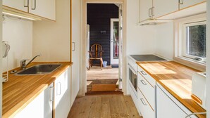 Une cuisine étroite avec des plans de travail en bois, un évier et une cuisinière.