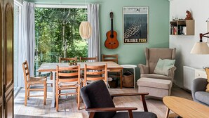 Un coin repas avec une table et des chaises en bois, une guitare et une affiche accrochée au mur.