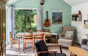 Un comedor con una mesa y sillas de madera, una guitarra y un cartel en la pared.