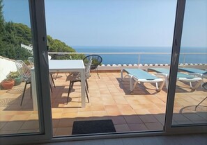 Enjoy the breathtaking sea views from this spacious outdoor space, featuring a table, chairs, and comfortable sun loungers.
