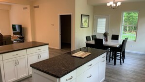 Une cuisine moderne avec des meubles blancs, des plans de travail en granit et un coin repas comprenant une table et des chaises.