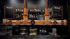A bar area with copper beer taps, shelves of liquor bottles, and a chalkboard menu listing cakes and desserts. - Biloela Hotel (Biloela)