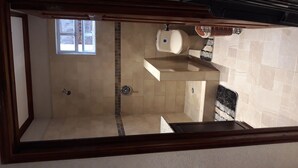 A bathroom with a toilet, shower, and a window. - Airconditioned suite (Castries)