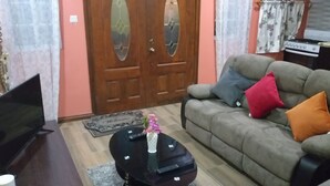 A living room with a sofa, a coffee table, a TV, and a door with glass panels. - Airconditioned suite (Castries)