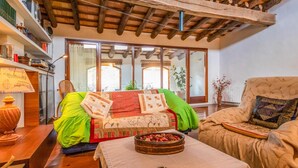 Una sala de estar acogedora con techo de madera, un sofá con cojines de colores, una silla y una mesa con una bandeja decorativa.