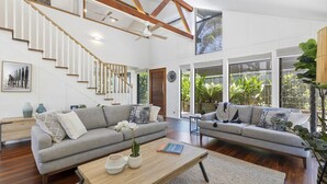 Ein geräumiger Wohnbereich mit zwei grauen Sofas, einem Holztisch und einer Treppe mit weißen Geländern.