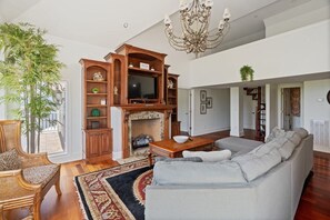 A spacious living room with a fireplace, a television, and a large sofa.