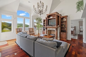 A spacious living room with a large sofa, a television, and a fireplace.