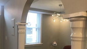 A room with a wooden floor, a brown leather chair, a small table with a lamp, and a window with blinds. - Esther's Place-Carleton Place Downtn Apt (Carleton Place)