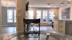 A spacious room with a large window, a dining table, and a modern kitchen area. - Esther's Place-Carleton Place Downtn Apt (Carleton Place)