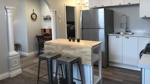A modern kitchen with a central island, stainless steel appliances, and a chandelier. - Esther's Place-Carleton Place Downtn Apt (Carleton Place)