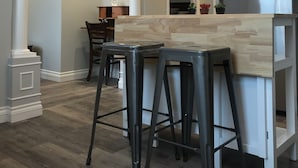 A modern kitchen with a large refrigerator, wooden bar stools, and a chandelier. - Esther's Place-Carleton Place Downtn Apt (Carleton Place)
