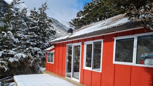 Un bâtiment rouge doté de grandes fenêtres et d’une terrasse en bois.