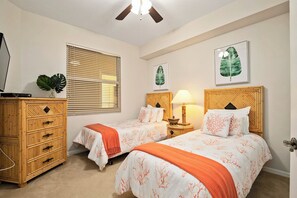 A bedroom with two beds, a wooden dresser, a ceiling fan, and a window with blinds. - Regatta - William Raveis Rentals (Naples)