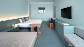 Moderni hotellihuone, jossa on sänky, yöpöytä ja seinälle asennettu televisio.