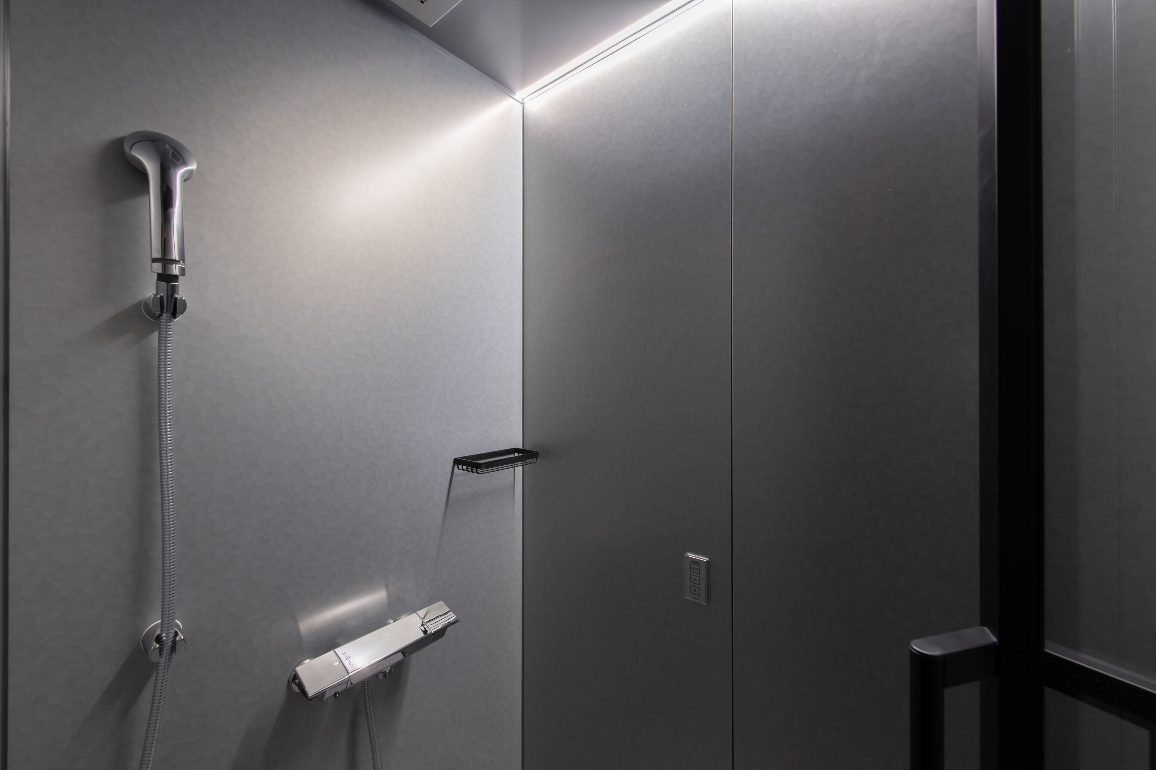 Un baño moderno con ducha, toallero y panel de control.