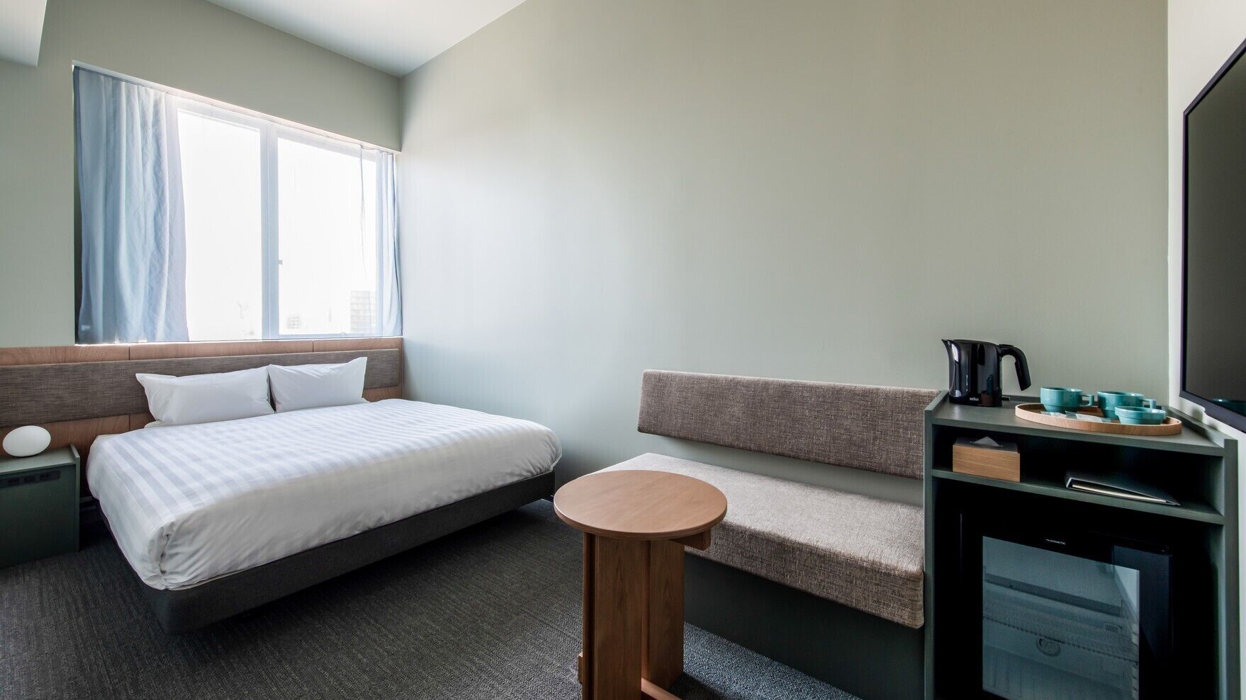 Een hotelkamer met een bed, een zithoek, een tafeltje, een televisie en een koffiezetapparaat.