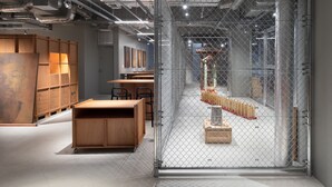 A modern interior with a chain-link partition, wooden furniture, and a visible staircase.