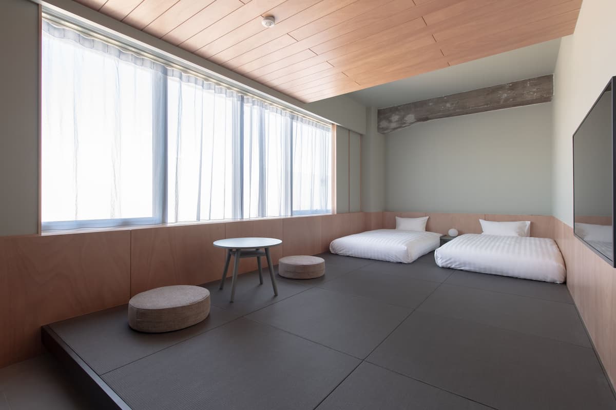 A modern room with a large window, a round table, and two beds.
