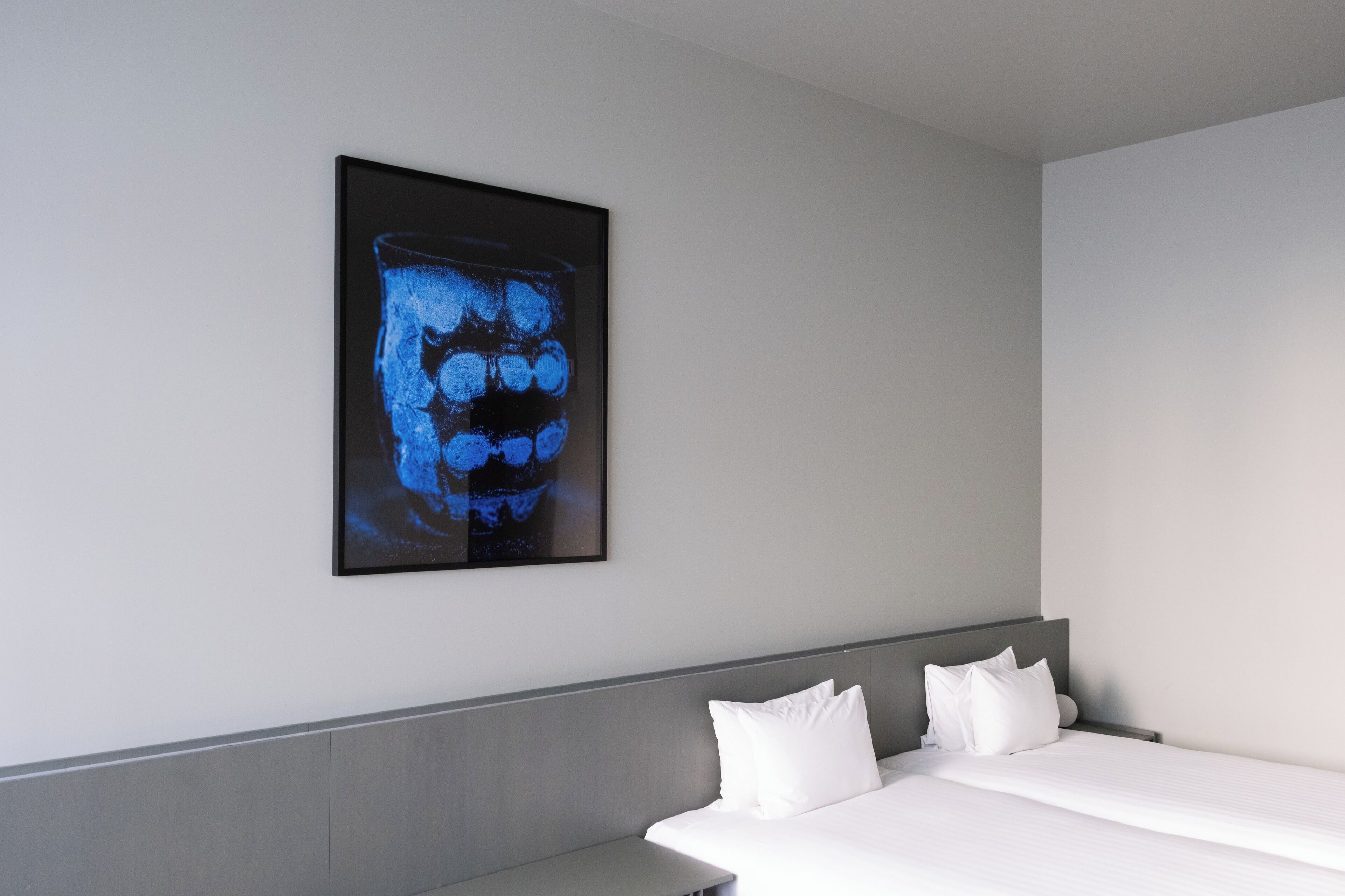 Ein modernes Hotelzimmer mit einem großen Bett, einem Kopfteil und einem an der Wand befestigten Kunstwerk.