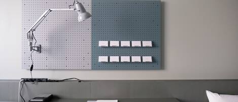 A workspace with a pegboard, desk, chair, lamp, and a laptop.
