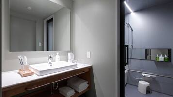 A modern bathroom with a large mirror, a sink, and a shower area.
