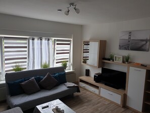 Relax in this inviting living room with a comfortable sofa, flat-screen TV, and cabinet.