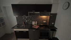 A modern kitchen with dark cabinetry, a dishwasher, an oven, and a sink. - Apartment Come-Home (Hohnstedt)