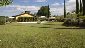 Una villa con piscina, mobiliario exterior y jardín.