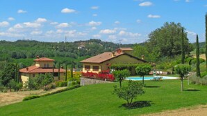 Una villa con piscina, rodeada de vegetación exuberante y colinas al fondo.