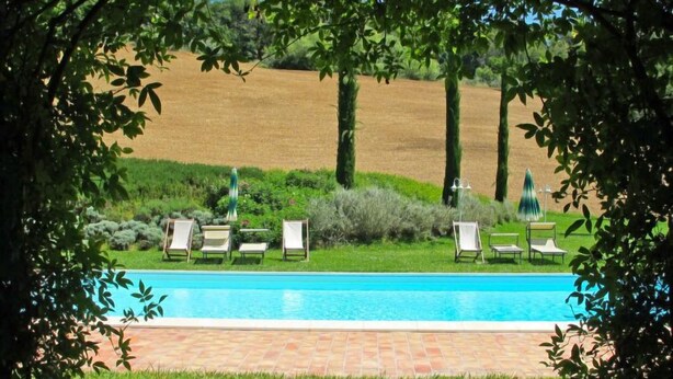 Una piscina con sillas de descanso y un sendero de ladrillos.