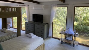 A bedroom with a TV, a dresser, and a window with a view of greenery. - Waterfront…Location is everything! (Littleton)
