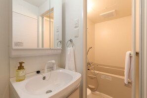 A bathroom with a white sink, a mirror, a towel ring, and a shower area. - The Grand Residence Hotel Hakata (Fukuoka)