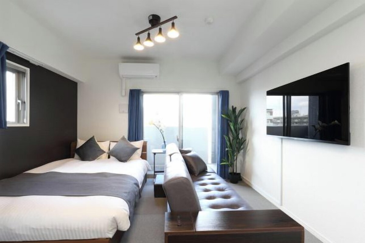 Una habitación de hotel moderna con una cama grande, un sofá, un televisor y un balcón con vistas.