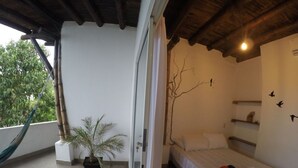 A bedroom with a bed, a potted plant, and a hammock.