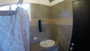 A compact bathroom with a shower curtain, a sink, and a toilet.
